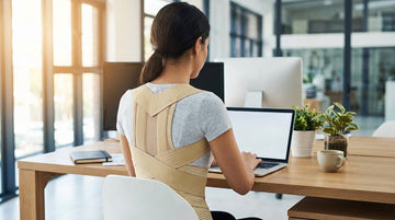 Person wearing ORTONYX posture corrector brace at office desk demonstrating proper posture