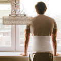 Man by a window wearing a white 10.25 in umbilical hernia belt, breathable elastic abdominal binder for navel/ventral support